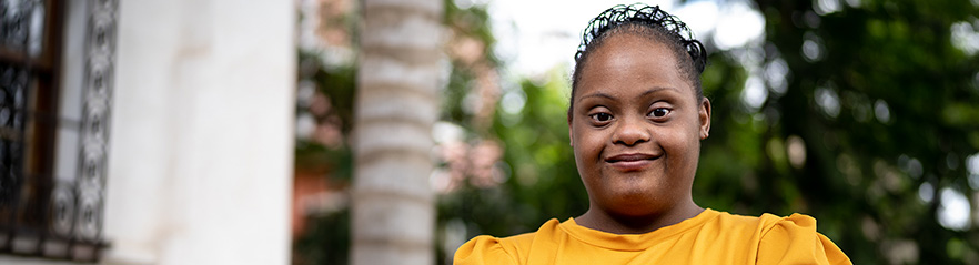 A young women outside a building looks towards the camera